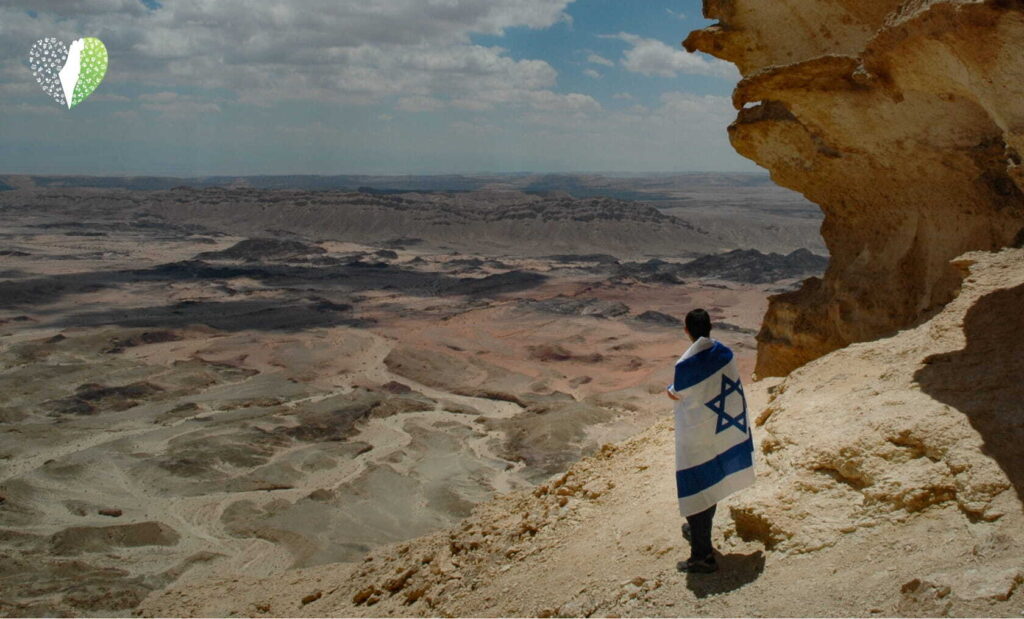A family stands on a desert hill overlooking the vast Negev landscape