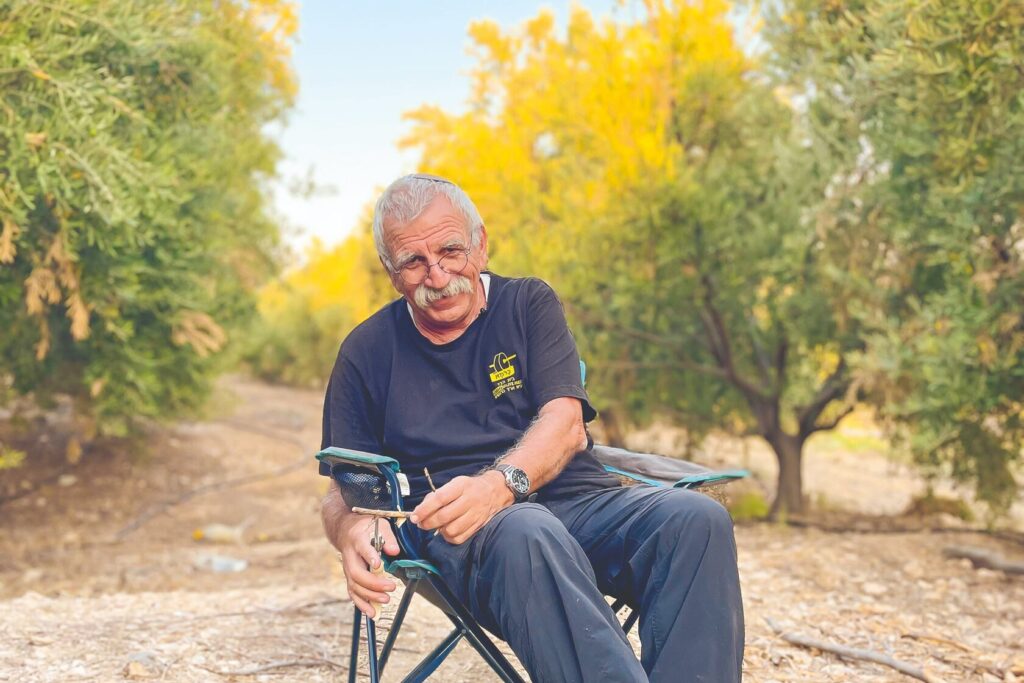 Boaz Ido holding a bottle of olive oil in an olive grove